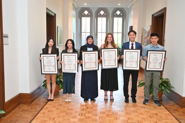 The six President&rsquo;s Engagement Prize winners holding framed certificates in College Hall